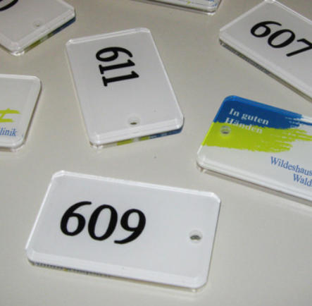 Plexiglas-Anhänger mit gedruckten Logo und gravierten Raumnummern